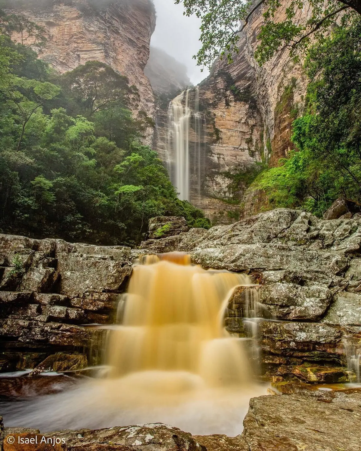 Tall waterfall falling between layered rock walls