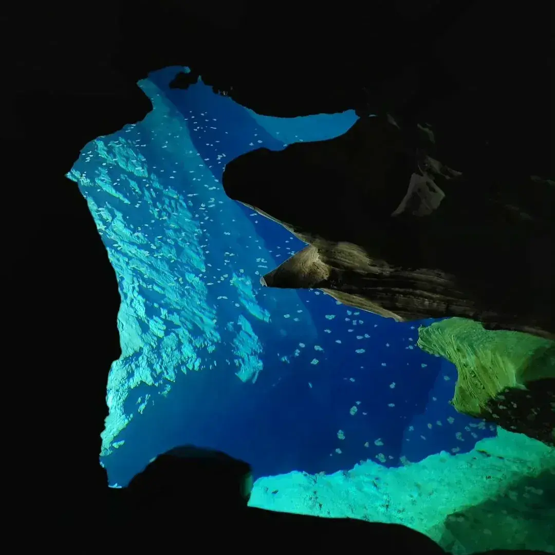 Deep blue water lit through the opening of a dark cave