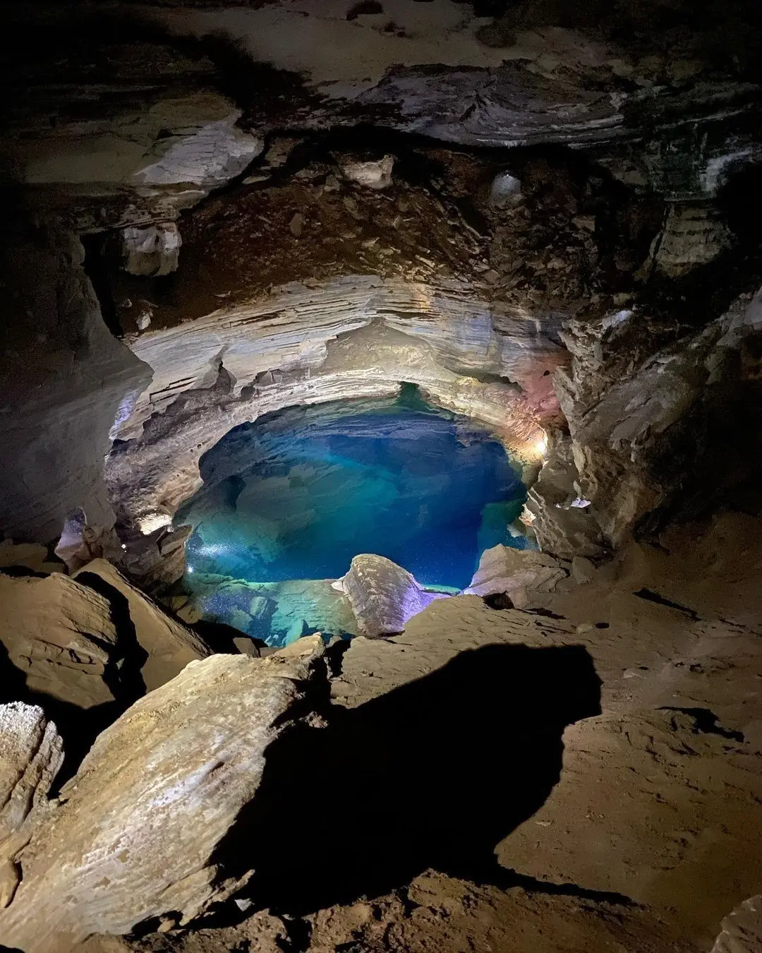 Small pool of blue water inside a dark cave