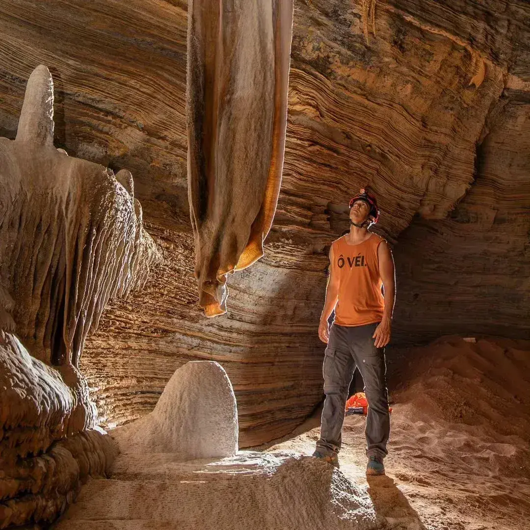 Person in a helmet among limestone formations inside a cave