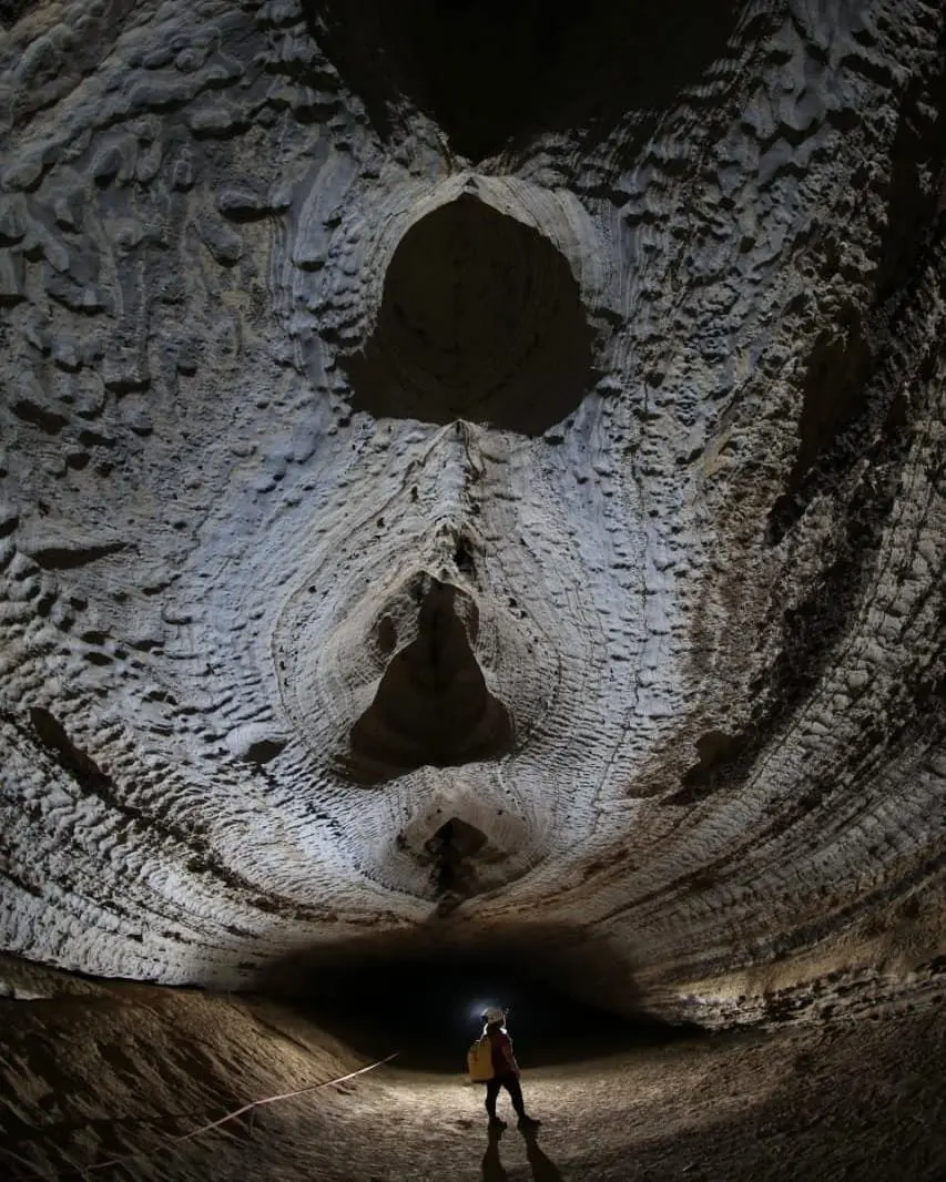 Cave chamber with a ceiling carved by water and a person in a helmet