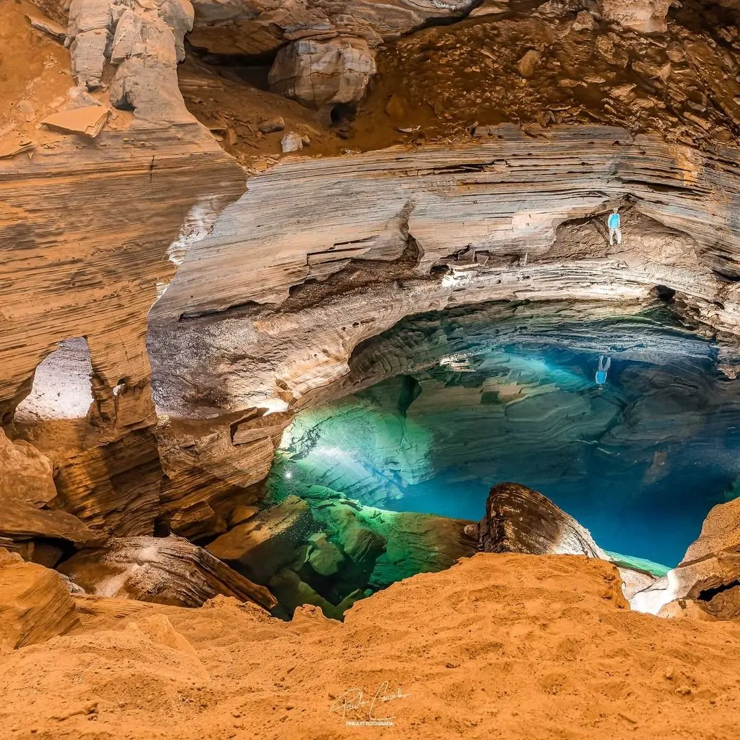 Poço do Lima seen from high in the cave: blue-green water among orange rocks