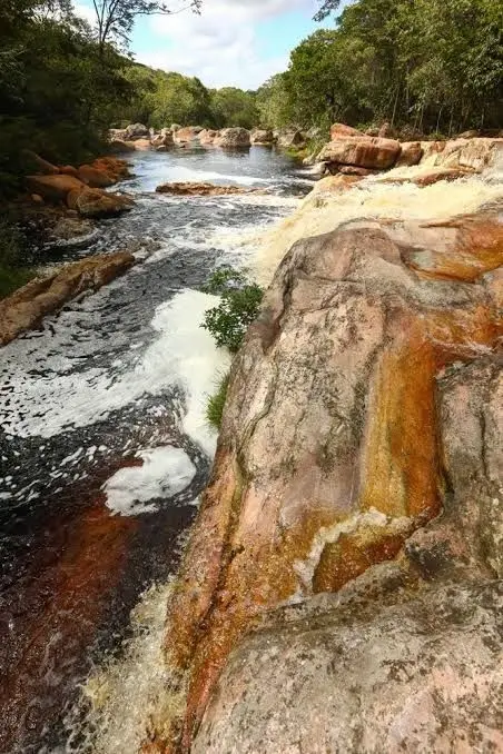 River with white foam flowing down between orange stone slabs
