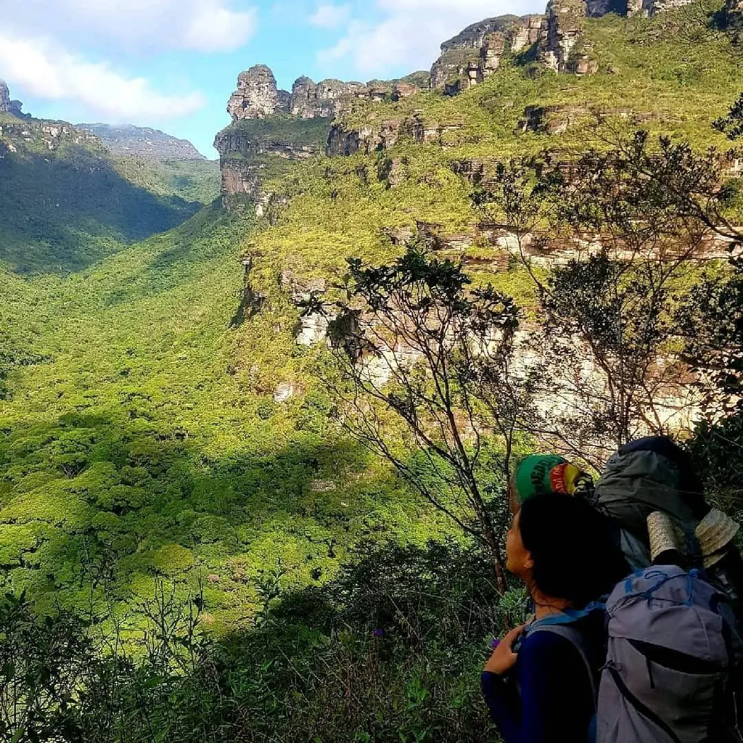 Hiker seen from behind looking at the Vale do Pati surrounded by cliffs