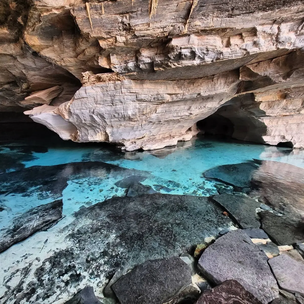 Gruta da Pratinha: agua turquesa transparente bajo una pared de roca clara y oscura