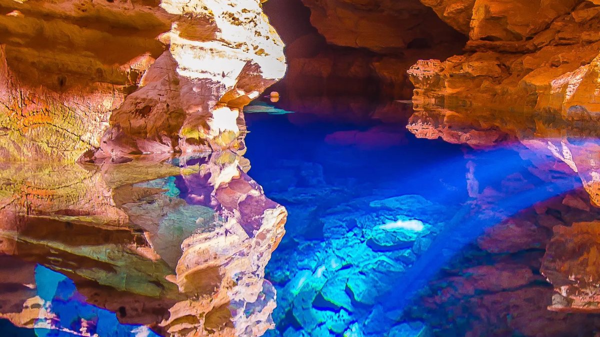 Haz de luz azul atravesando el agua transparente del Poço Encantado, en el fondo de la cueva