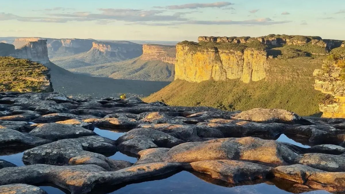 Charcos de agua en la roca plana de la cima del Pai Inácio y cerros de meseta iluminados por el atardecer